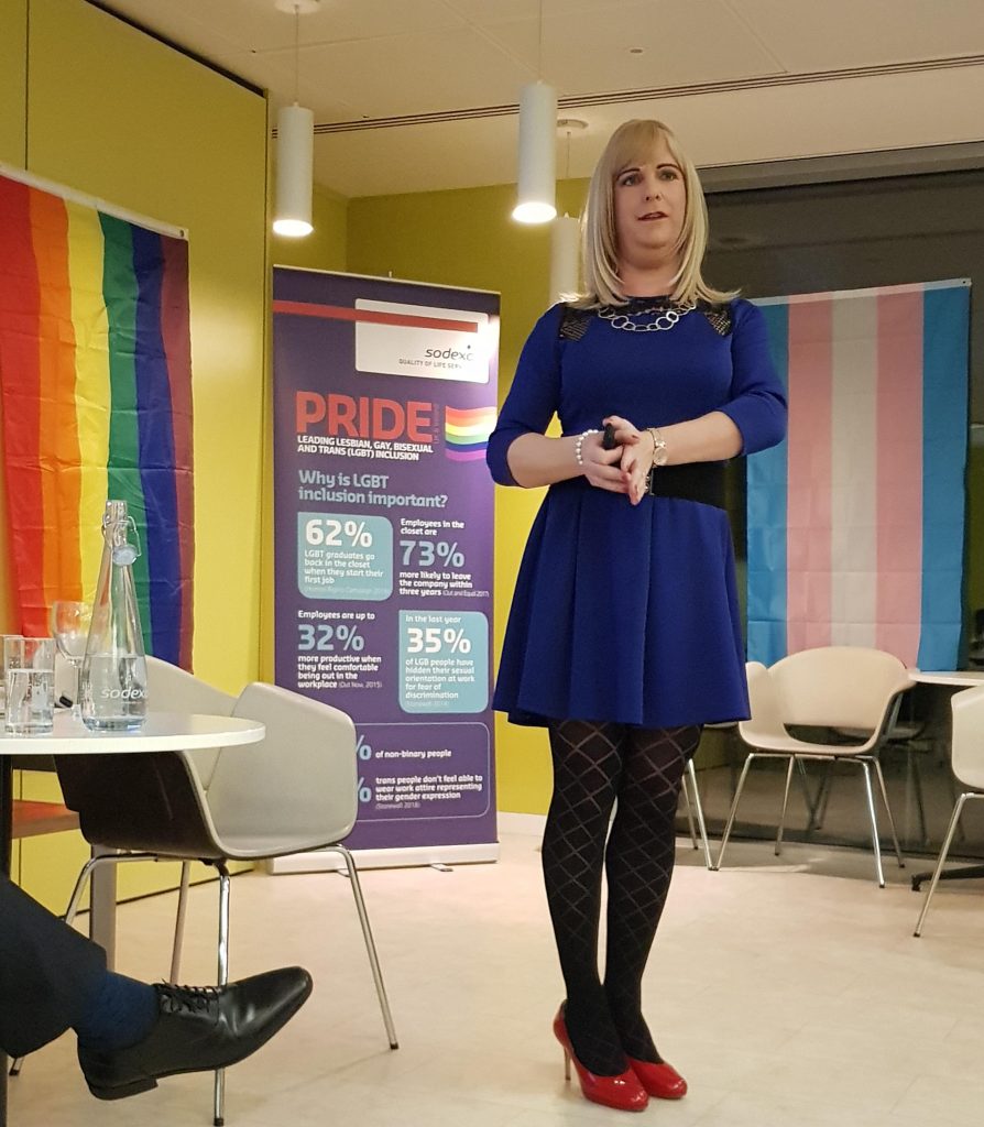 Pips Bunce hosting a session, standing at the front of the room presenting as part of a Sodexo hosted Pride event