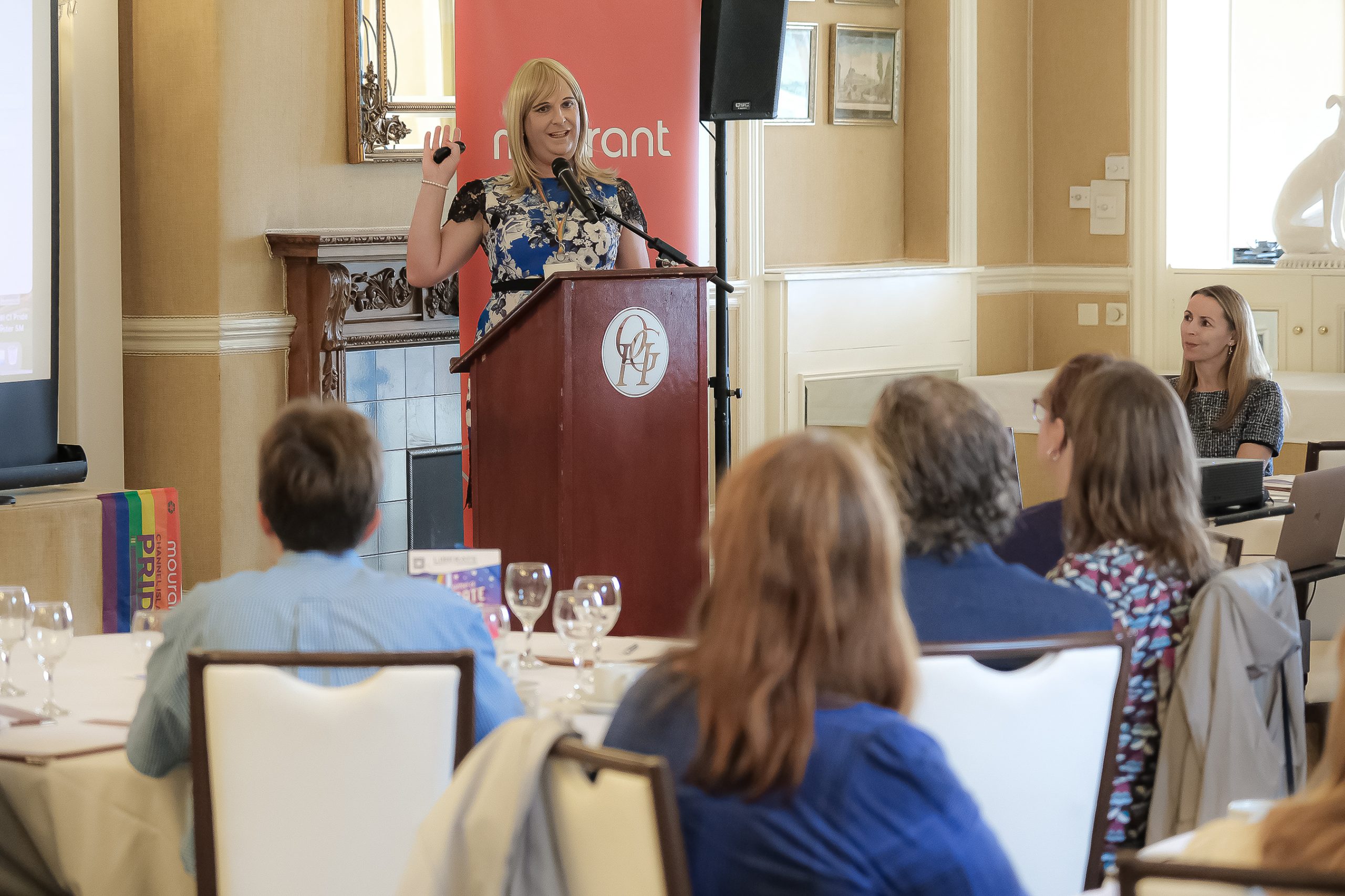 Pips Bunce, founder of Humility Hub, standing behind a podium delivering a session to a room full of engaged attendees