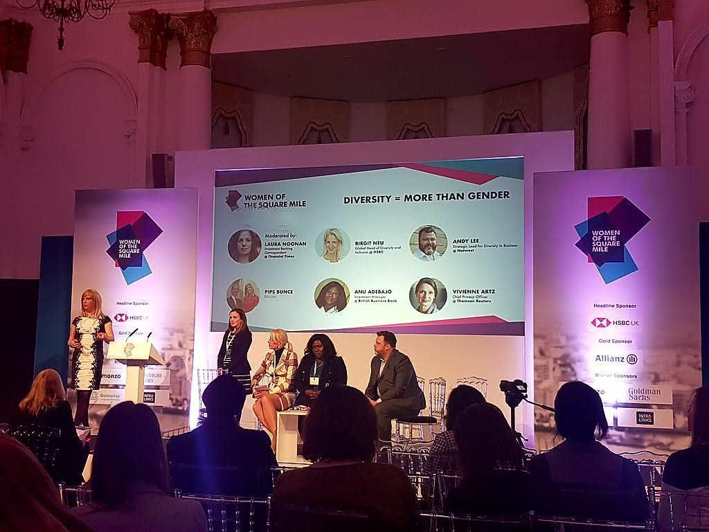 Pips Bunce standing on a stage presenting as part of a panel. In this she is facing the audience and speaking to the audience