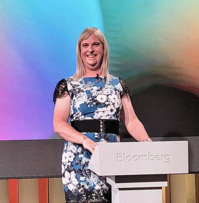Pips Bunce presenting to a group standing behind a Bloomberg podium